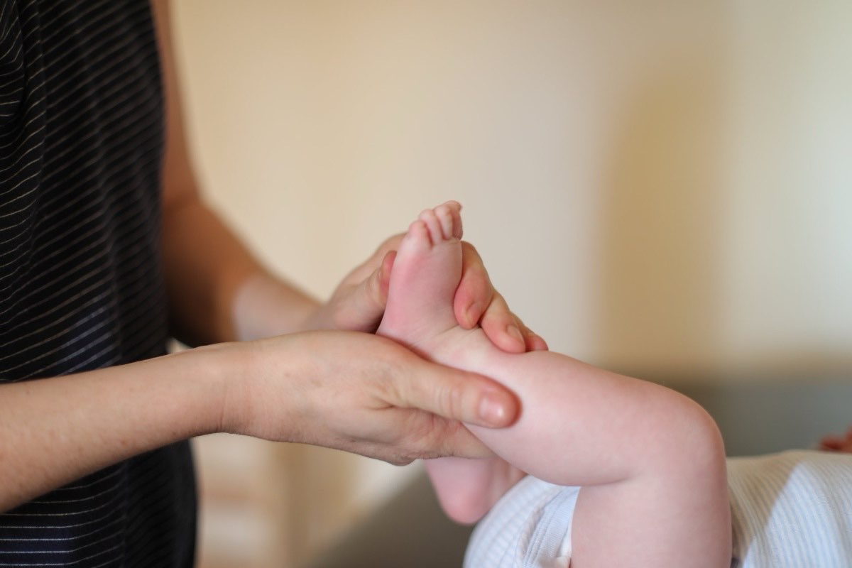 Physiotherapeutin behandelt behutsam den Fuß eines Säuglings in der Praxis